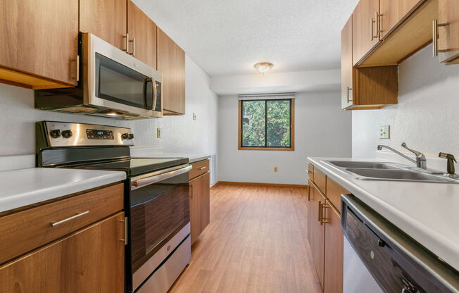 an empty kitchen with wooden cabinets and stainless steel appliances