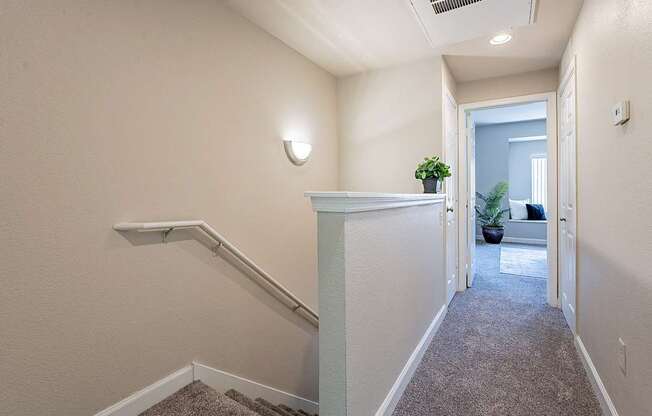 A hallway with a carpeted floor and a staircase on the left side.at Palazzo Townhomes, Phoenix, AZ 85008  