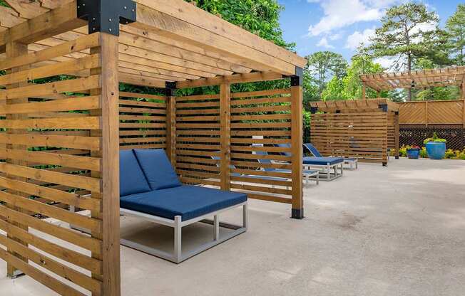 A wooden pergola with a blue cushioned bench underneath it. at Mill House at East Cobb, Marietta