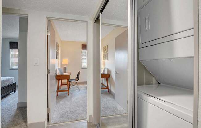 A white refrigerator is in the kitchen area of a small apartment.