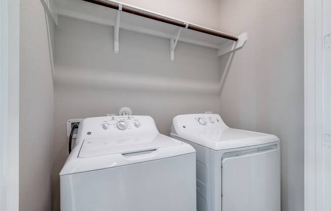 a washer and dryer in a laundry room with a shelf over the top