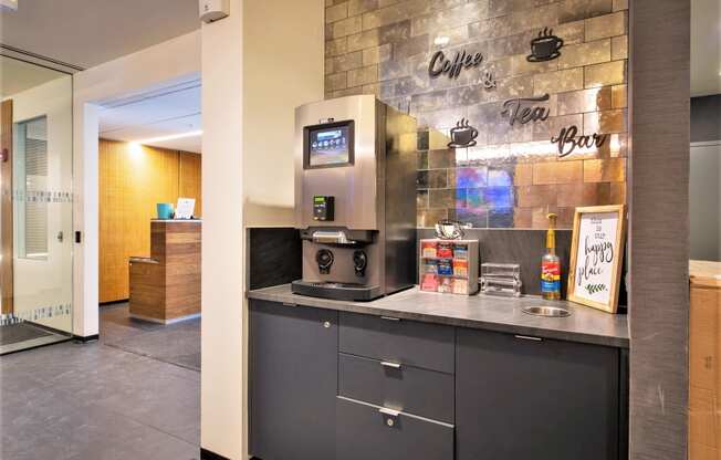a counter with a coffee machine and a sink in front of a brick wall at One 333, Chicago, 60605