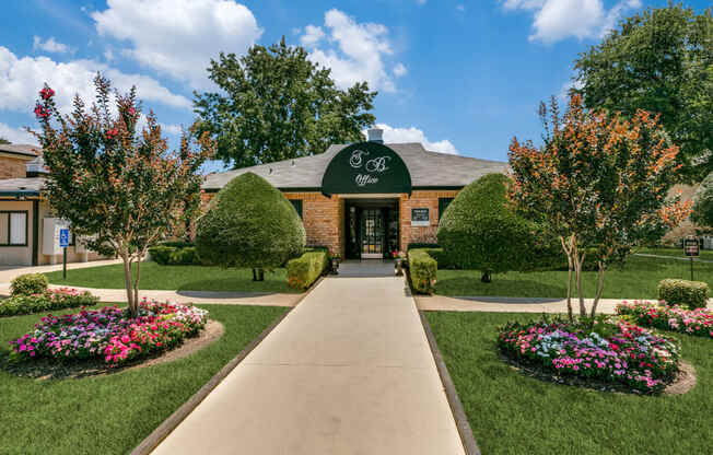 an exterior view of a brick building with a green awning and landscaping