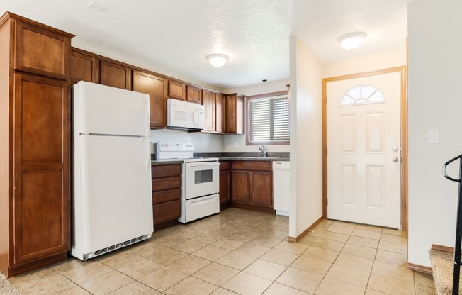 a kitchen with brown cabinets and white appliances