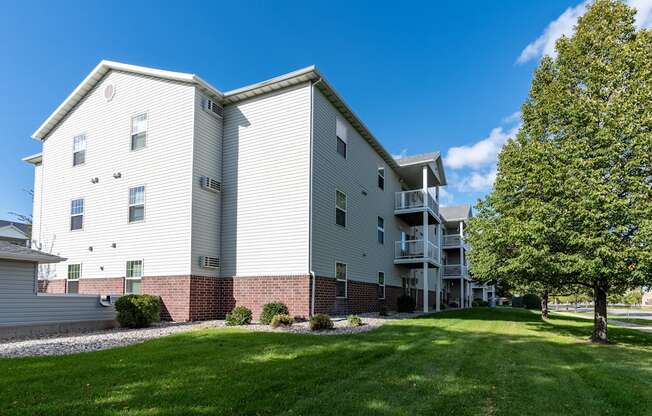 An exterior of an apartment with a grassy area out front.