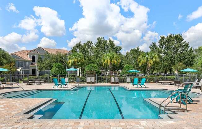 A large swimming pool surrounded by blue lounge chairs and umbrellas.