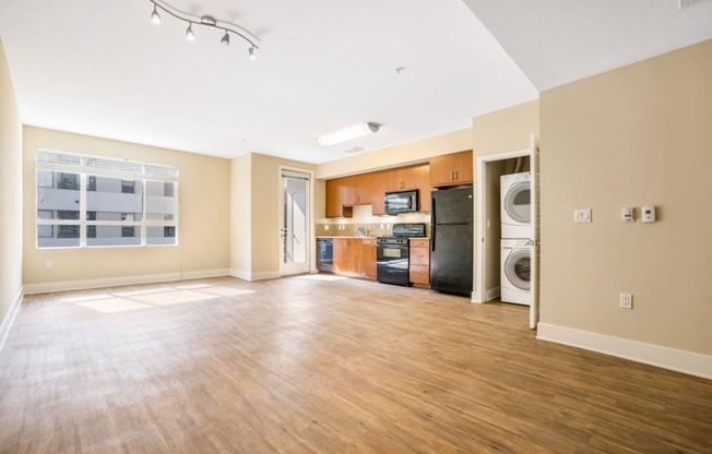 an empty living room with a kitchen and washer and dryer