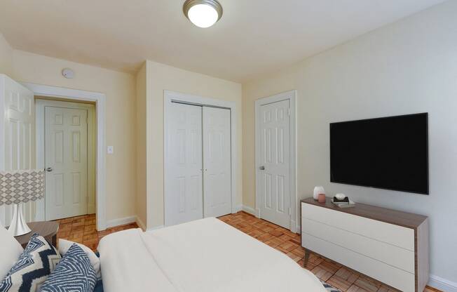 Bedroom with bed, dresser, tv, and large closet at sherry Hall apartments in washintgon dc