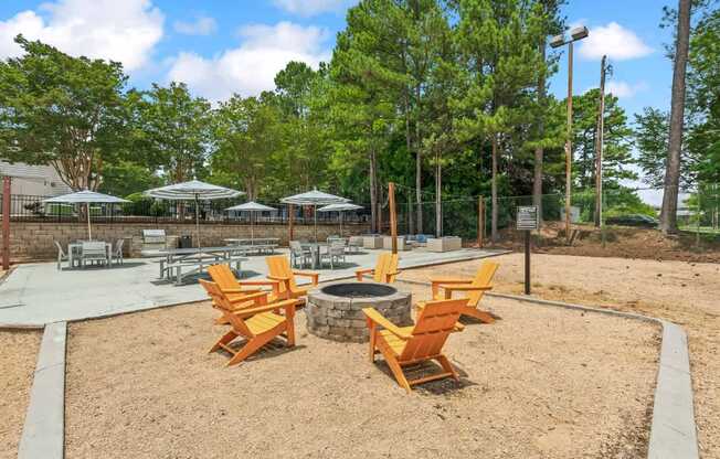 A park with a fire pit and chairs.