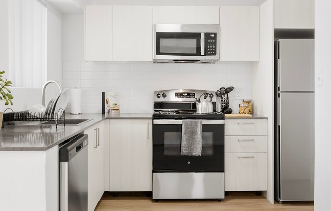 A modern kitchen with white cabinets and stainless steel appliances.