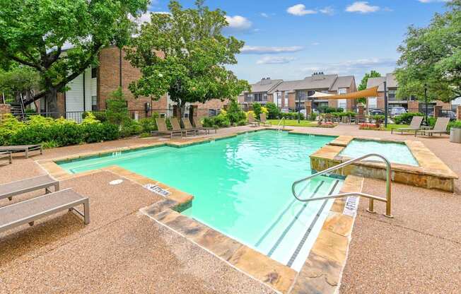 A pool surrounded by a concrete patio and a grassy area.