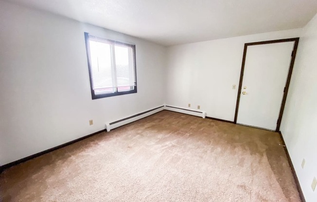 an empty living room with white walls and a window