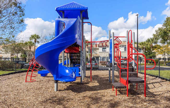 A playground with a blue slide and red climbing structures.