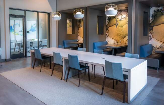 a dining room with a long white table and blue chairs