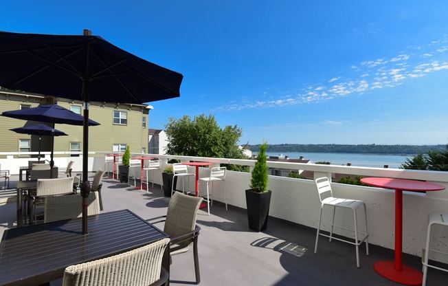 A patio with tables and chairs overlooking a body of water.
