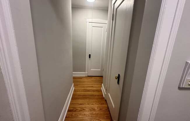 a small hallway with a white door and wood floors