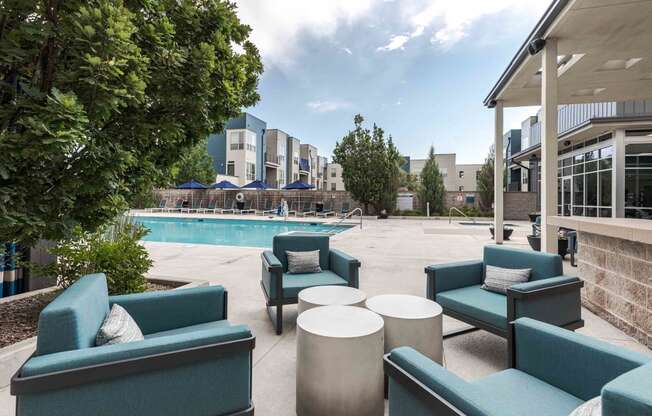 a swimming pool with blue chairs and a patio with tables