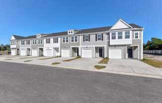 Townhomes for Rent in North Charleston, SC - Highland Townhomes - Street View of Townhomes with White and Grey Walls, Garages, and Spacious Concrete Driveways.