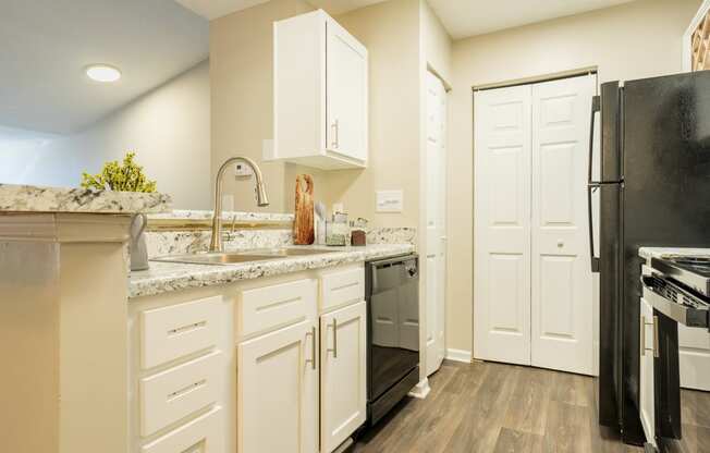 a kitchen with white cabinets and stainless steel appliances and a black refrigerator