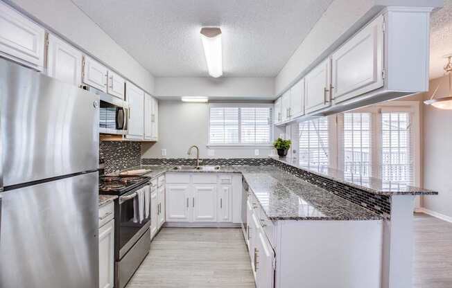 A kitchen with white cabinets and a granite countertop.