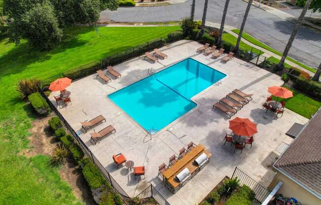 Drone footage of the community pool area showing sun deck with lounge chairs and gas BBQs 