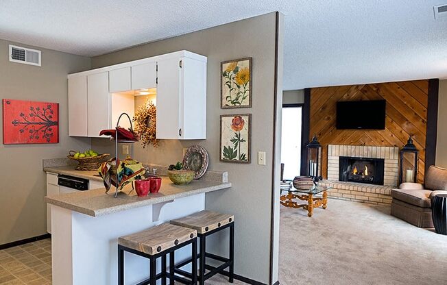 a kitchen with a counter and a living room with a fireplace