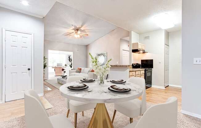 a dining area with a table and chairs and a kitchen in the background