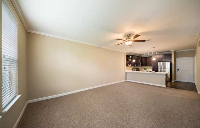 an empty living room and kitchen with a ceiling fan