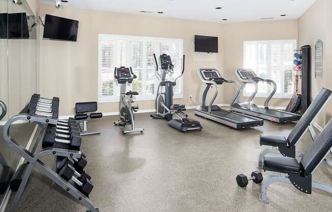 A spacious gym with a variety of equipment including treadmills, stationary bikes, and weight machines.
