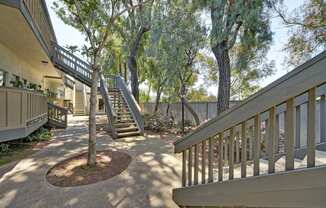 a patio with stairs and trees in front of a house