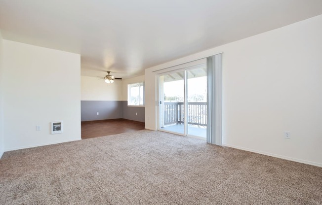 an empty living room with a sliding glass door and a balcony