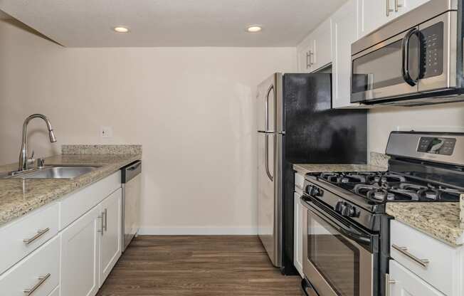 an empty kitchen with white cabinets and stainless steel appliances and a black stove and refrigerator at Rocklin Manor  Apartments, Rocklin  , California