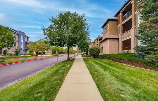 the view of a city street with apartment buildings and grass and trees