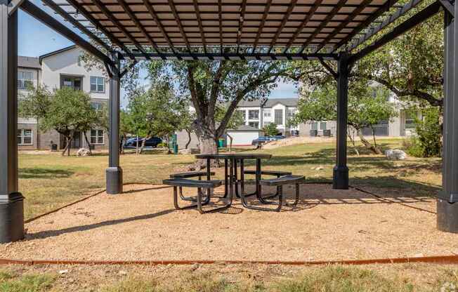 A picnic table is set up under a canopy in a park.