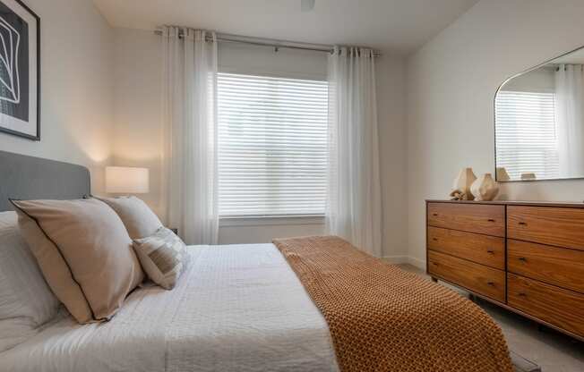 a bedroom with a bed and a dresser and a window