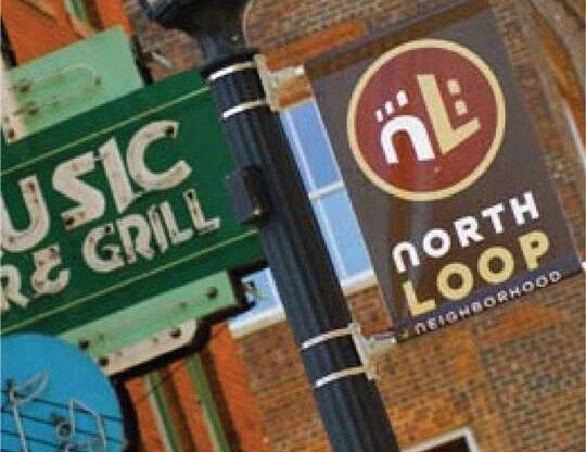A sign for a music venue is hanging from a pole.