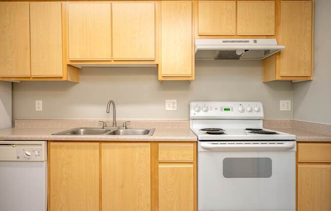 A kitchen with a white stove and wooden cabinets.