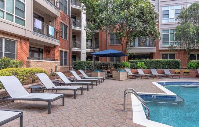 A pool surrounded by lounge chairs and umbrellas.