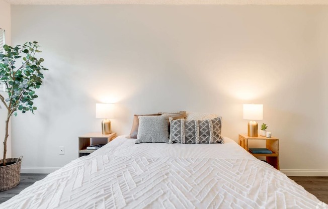 a bedroom with a large white bed and white walls at University Park, Azusa