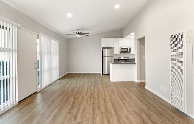 an empty living room and kitchen with wood flooring