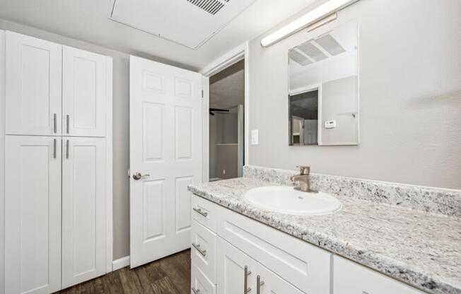 Model bathroom with a sink, mirror, and cabinets.
