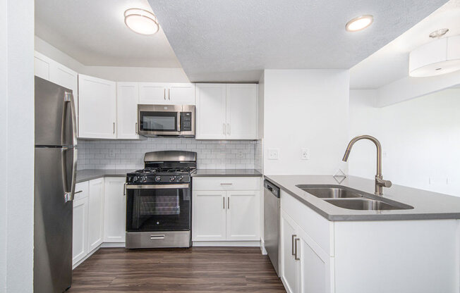 two bedroom kitchen with white cabinets and stainless steel appliances