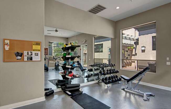 A gym with a variety of equipment including weights and a bench.