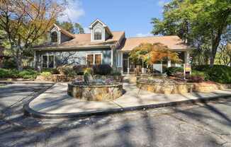 A house with a grey roof and a stone fountain in front.