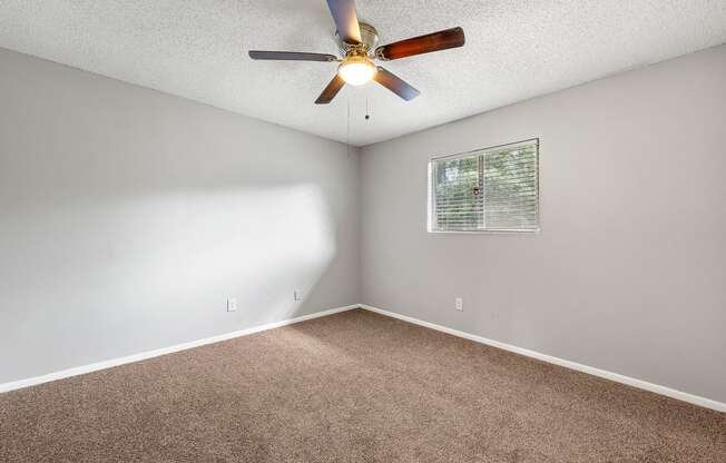 an empty room with a ceiling fan and a window