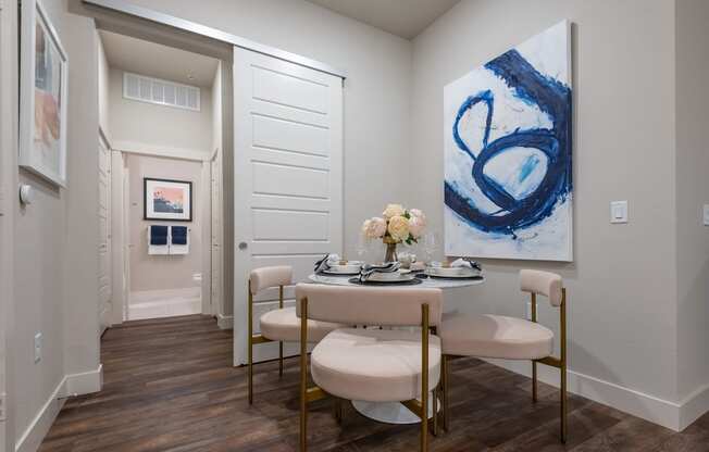 a dining room with a table and chairs with a vase of flowers on top of it