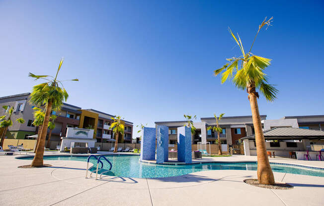 a swimming pool with palm trees and buildings in the background