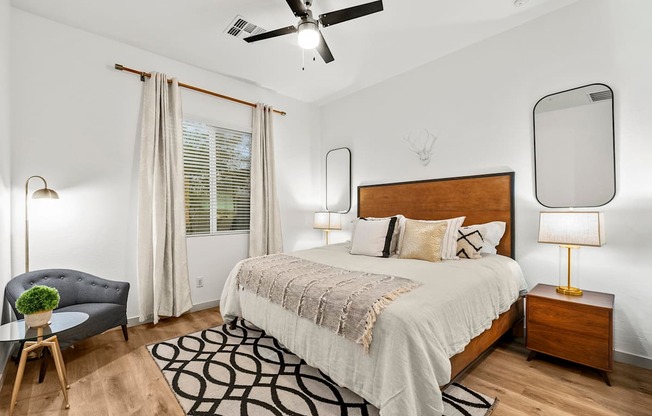 A bedroom with a large bed, a ceiling fan, and a chair.