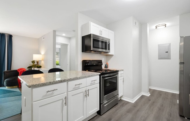 a kitchen with white cabinetry and a counter top with a stove and a microwave