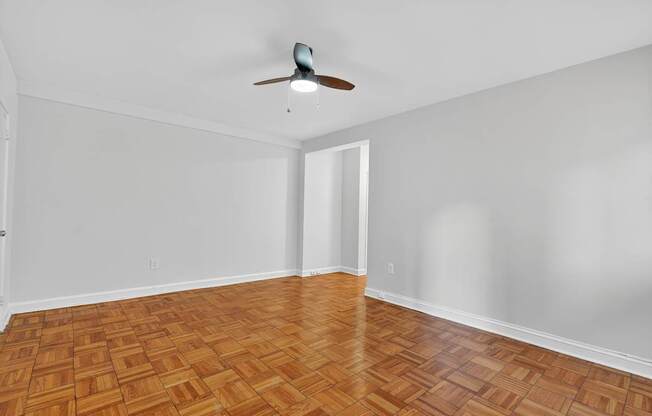 A room with a ceiling fan and wooden flooring.